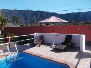 a patio with two chairs and an umbrella next to a pool at Casa Teresa in El Paso