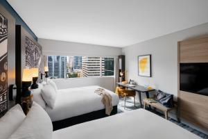 a hotel room with two beds and a tv at voco Brisbane City Centre by IHG in Brisbane