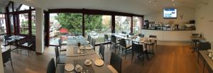 a restaurant with tables and chairs in a room with windows at Hotel garni Kaiserstuhl in Ihringen