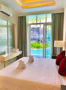 a bedroom with a large white bed with a desk and a window at Grand florida pattaya beach front in Na Jomtien