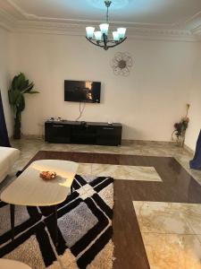 Una sala de estar con un sofá, una mesa y un televisor. en BaRaN HOME, en Yaoundé