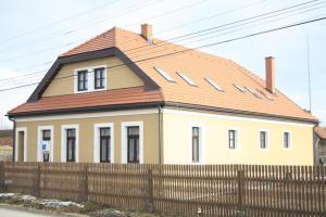 a yellow house with a red roof behind a fence at Pensiune AgroTuristica Horváth-Kert in Borzont