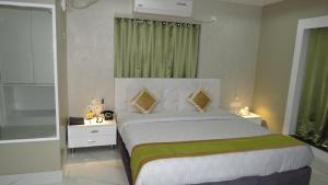 a bedroom with a large white bed with green accents at Geetanjali International in Deoghar +48 photos