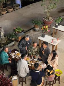 eine Gruppe von Menschen sitzt um einen Tisch herum und isst in der Unterkunft Thương Thương Đà Lạt 2 in Xuan An