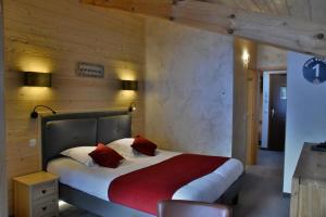 a bedroom with a large bed with red pillows at Hôtel Les Côtes, Résidence Loisirs et Chalets in Morzine