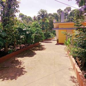 a sidewalk next to a yellow building with trees at Aghasthyashrya Homestay in Siddapur +9 photos