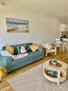 a living room with a blue couch and a table at Golden sunset in Glenelg