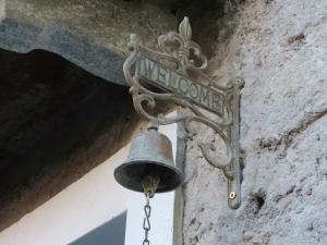 eine Glocke hängt von einem Gebäude mit einem Straßenschild in der Unterkunft Guesthouse "Castello del Nucleo" in Intragna