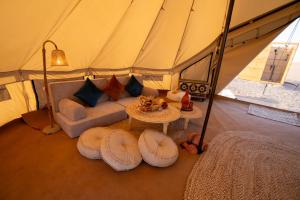 a tent with a couch and a table in a room at Twilight Dunes by Miracle Oman in Badīyah