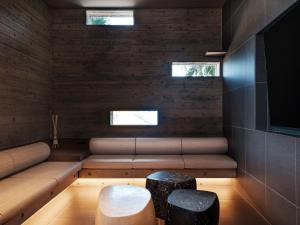 a room with a couch and two stools and a television at Iluvio Resort Motobu in Motobu