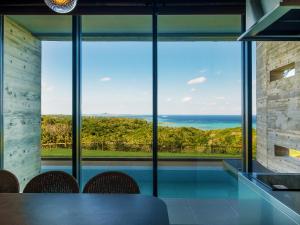 a dining room with a view of the ocean at Iluvio Resort Motobu in Motobu