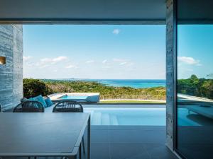 a house with a pool and a view of the ocean at Iluvio Resort Motobu in Motobu