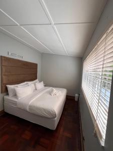 ein Schlafzimmer mit einem Bett mit weißen Laken und einem Fenster in der Unterkunft Everly4 Guest Apartment in Durban