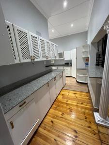 eine Küche mit weißen Schränken und einem Holzboden in der Unterkunft Everly4 Guest Apartment in Durban