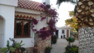 Una casa con flores púrpuras a un lado. en Chalet Atalants Yailja, en Alcossebre