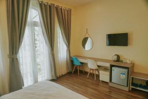 a bedroom with a bed and a desk and a window at Hotel Tường Vy 3 in Da Lat