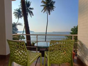 a balcony with a table and chairs and the ocean at GS Home on the Bay - Super Sea view glass studio apartment in Vagator