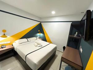 a bedroom with a bed and a desk and a television at Smile Hotel Balakong Kajang in Cheras