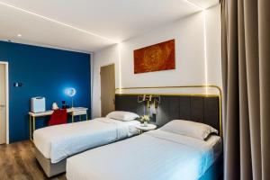two beds in a hotel room with blue walls at Regatta at Kozi Square Kuching in Kuching