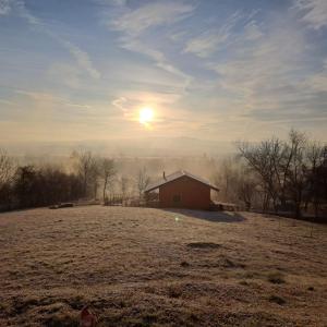 a barn in a field with the sun in the sky at Cabana Laura in Tîrnăveni