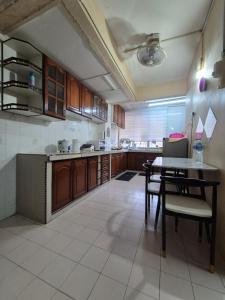 a kitchen with wooden cabinets and a table and chairs at Perindu Homestay IM2 in Kuantan