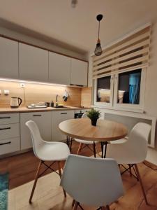 a kitchen with a wooden table and white chairs at Mons Apartments Jahorina in Jahorina
