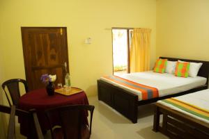 ein Schlafzimmer mit einem Bett und einem Tisch und einem Fenster in der Unterkunft Leon Lakeside Hotel - Kataragama in Gotamegama