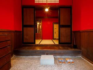 金沢市にある町家ホテル　町の踊場の赤い壁の客室で、床にスリッパが付いています。