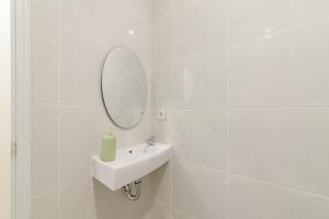a white bathroom with a sink and a mirror at Urbanview Hotel Vineyard Cengkareng in Jakarta