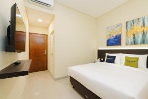 a white bedroom with a bed and a television at Urbanview Hotel Vineyard Cengkareng in Jakarta