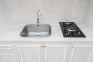 a kitchen counter with a sink and a stove at Comfort and Modern Studio at Tree Park Cikokol Apartment By Travelio in Tangerang