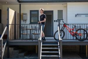 a man standing on the porch of a house with a bike at Maydena Lodge in Maydena