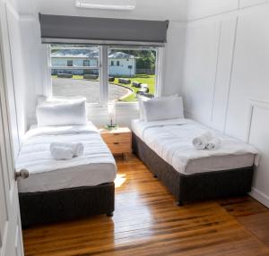 two beds in a room with a window at Maydena Lodge in Maydena