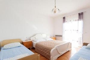 a white bedroom with two beds and a window at Apartments in Turanj 150 meters from the sea - By TA Leut Agency in Turanj
