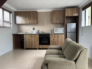 a kitchen with wooden cabinets and a couch in it at Aspire on Meier in East London