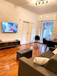 a living room with a couch and a tv on the wall at Iaru-Bed Experience House in Alberobello