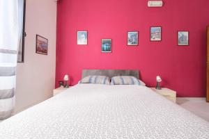 a bedroom with a large white bed with a red wall at Casa Via Medici in Milazzo