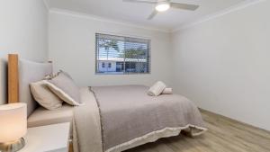 a white bedroom with a bed and a window at 'deja Blue' in Bongaree +9 photos