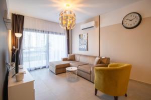 a living room with a couch and a clock on the wall at Ground Garden & Pool View Spacious Apartment at Caesar Resort & SPA in Mağusa