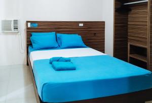 a bed with blue pillows on it in a room at RedDoorz at Sir G Hotel D'Mall Boracay in Boracay