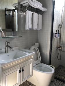 un bagno bianco con lavandino e WC di Stroll at Wudao Inn a Jinhu