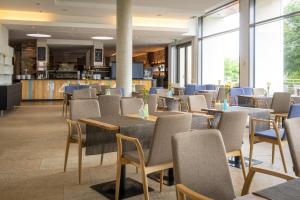 a dining room with tables and chairs and windows at LAGO hotel & restaurant am see in Ulm