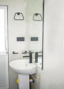 a white bathroom with a sink and a mirror at Sanasa Villa Weligama in Weligama