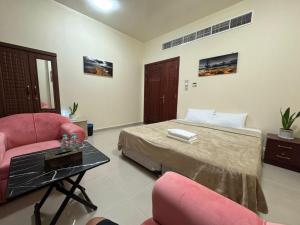 una camera da letto con un letto, due sedie e un tavolo di shared bathroom room a Al Ain
