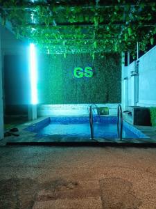 a swimming pool at night with a green wall at GS Homestay Banyuwangi in Banyuwangi