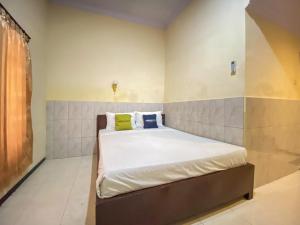 a bedroom with a bed with white sheets and yellow pillows at Surya Guest House Urbanview Probolinggo in Kanigaran +28 photos