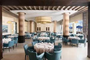 Un comedor con mesas y sillas y una lámpara de araña. en Atlas Essaouira Riad Resort, en Essaouira