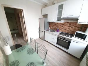 a kitchen with a table with chairs and a refrigerator at Apartment in The Heart of the Capital in Chişinău +10 photos