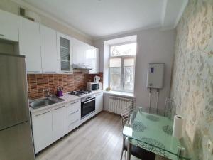 a small kitchen with white cabinets and a glass table at Apartment in The Heart of the Capital in Chişinău