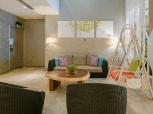 a living room with a couch and a table and chairs at A Hotel Joo Chiat, Stay From 7PM to 9AM in Singapore
